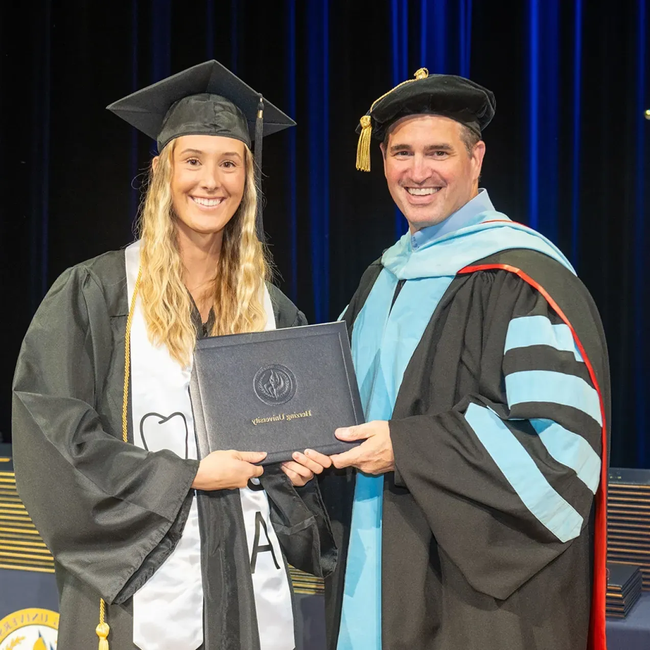 A Herzing University graduate receiving their diploma during a commencement ceremony, celebrating achievements in dental hygiene or dental assisting.